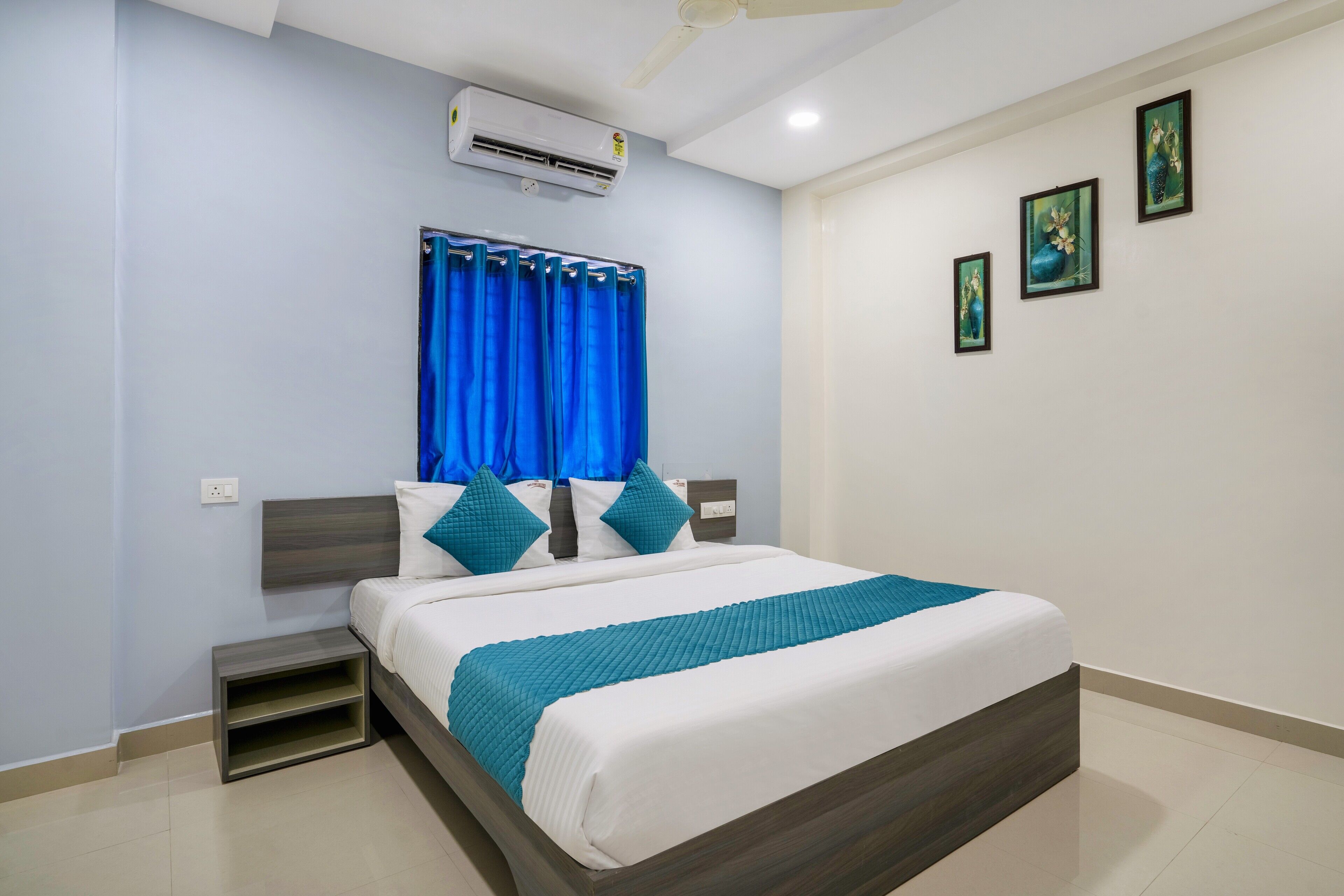 Une chambre moderne avec un grand lit, une table de chevet, un ventilateur de plafond et un appareil de climatisation.