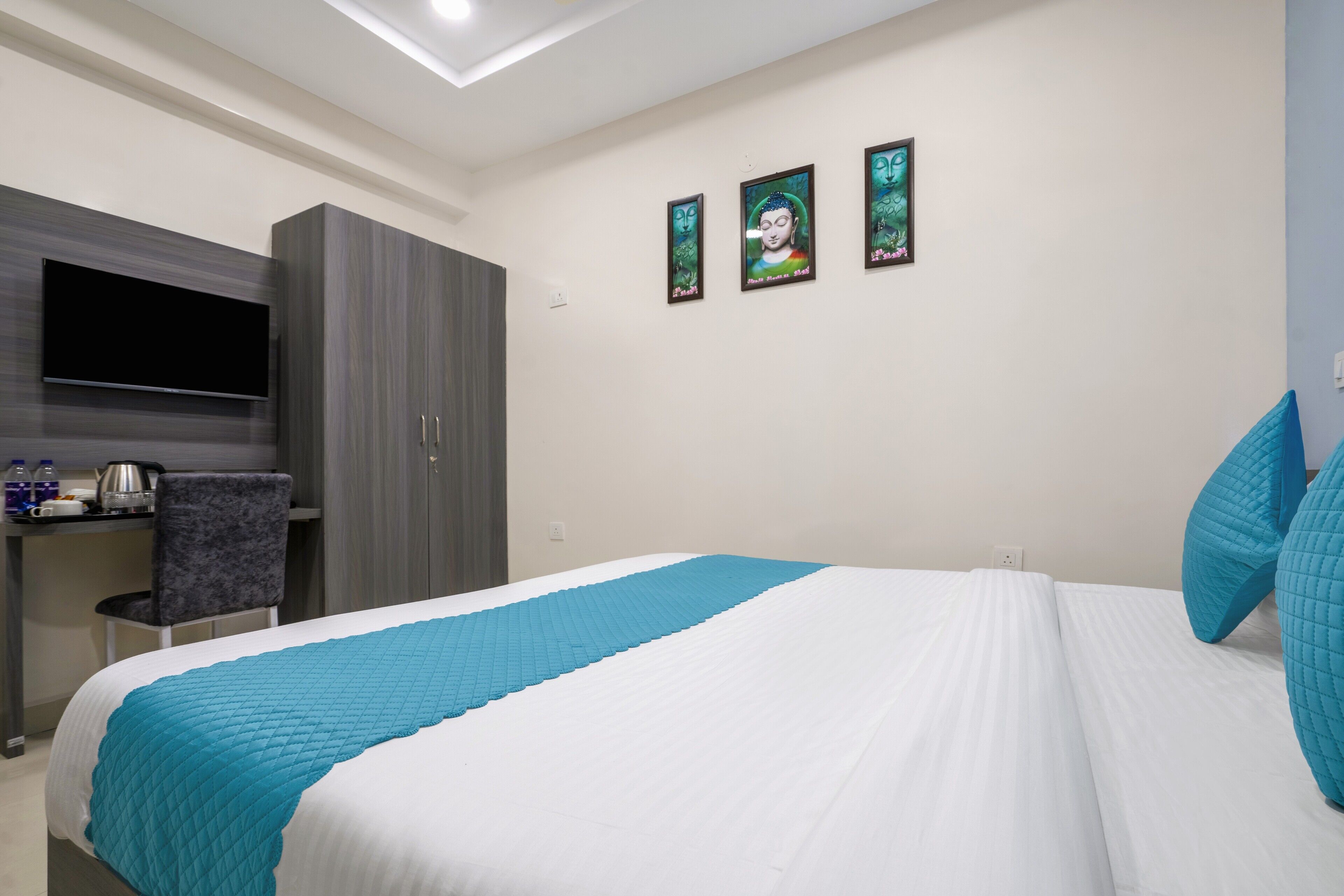 A hotel room with a bed, a desk with a flat-screen TV, and a wardrobe.