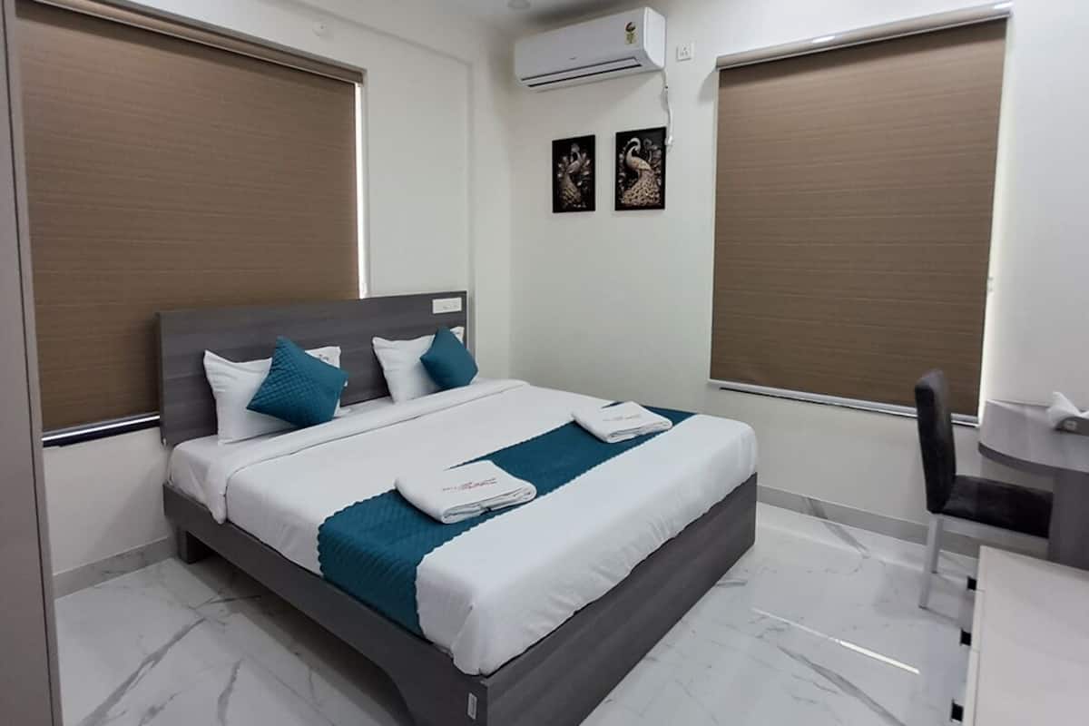 A modern hotel room with a bed, a desk, and an air conditioning unit.