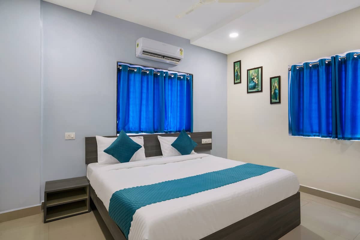 A neatly arranged bedroom with a bed, a nightstand, a built-in shelf, and a window with curtains.