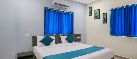 A neatly arranged bedroom with a bed, a nightstand, a built-in shelf, and a window with curtains.