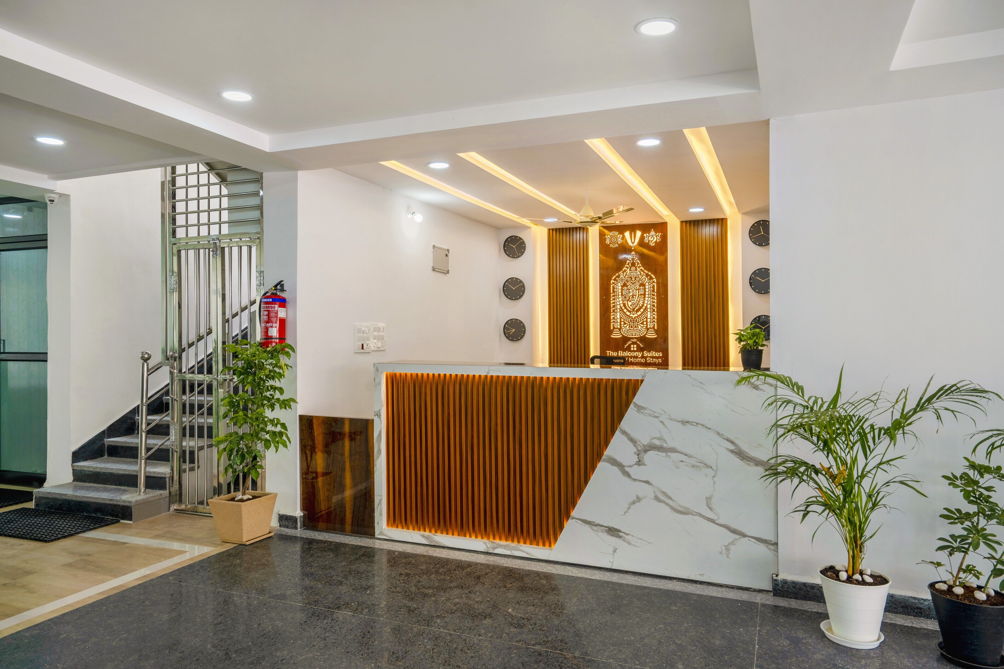 A reception area with a marble counter, a wooden panel, and a staircase.