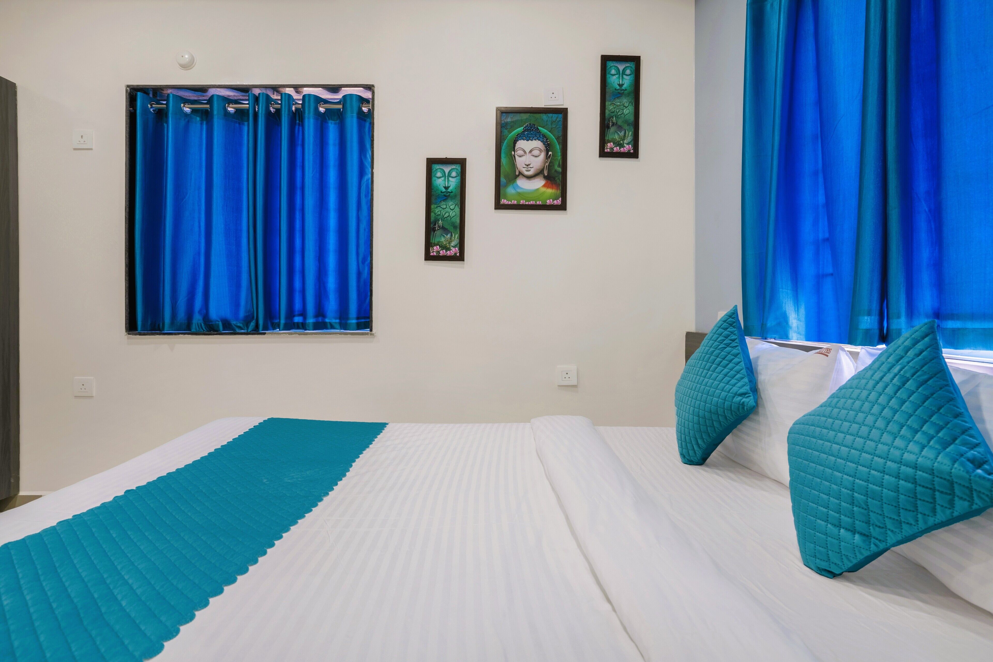 Un dormitorio con cama, cortinas azules y cuadros en la pared.