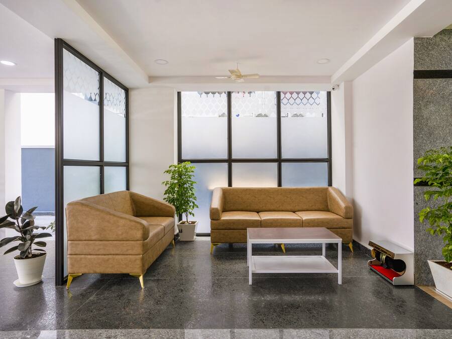 A modern waiting area with two sofas, a coffee table, and potted plants.