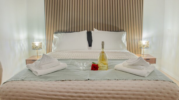 A neatly made bed with a bottle of wine, a rose, and towels. - Wonderful Apartment near the Vatican and Historical Center (Roma)