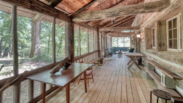 A rustic cabin with a wooden deck, large windows, and a bench area. - Rustic Historical Cabin near Wineries & Gold Mines (Dahlonega)