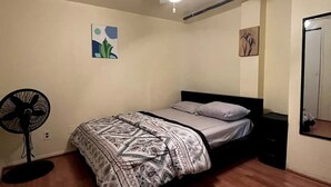 Une chambre à coucher avec un lit, un ventilateur de plafond et des œuvres d’art accrochées aux murs.