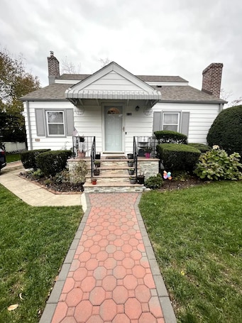 A two-story house with a front porch, a red hexagonal tile pathway leading to the door, and a well-maintained lawn.