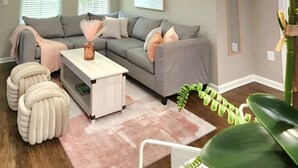 A modern living room with a grey sofa, a white coffee table, and a pink rug. - Cozy King Suite / Smart TVs / Self Check-In / Free Parking & Wi-Fi (Fort Mill)