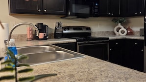 A kitchen with dark cabinets, a stainless steel sink, a microwave, and a coffee maker. - Cozy King Suite / Smart TVs / Self Check-In / Free Parking & Wi-Fi (Fort Mill)