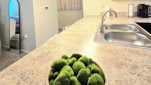 A modern kitchen with a granite countertop, stainless steel sink, and a hanging light fixture. - Cozy King Suite / Smart TVs / Self Check-In / Free Parking & Wi-Fi (Fort Mill)
