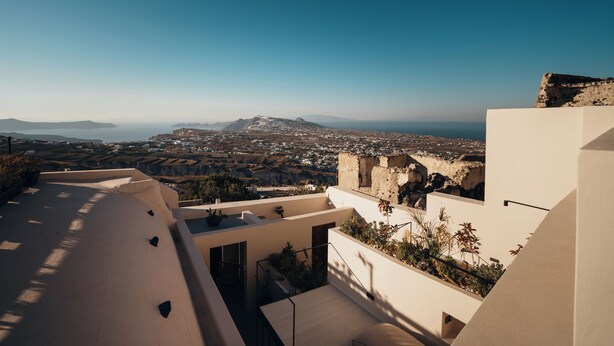 Un edificio moderno con una terraza en la azotea que da vistas a un paisaje costero.