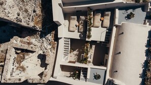 Vista aérea de un edificio moderno con varias zonas de estar, mobiliario exterior y una escalera que conduce a un nivel superior.