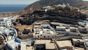 Un pueblo costero con edificios blancos, una iglesia destacada con campanario y vistas al mar.
