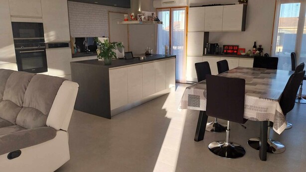 A modern kitchen with a central island, a dining area with a glass table, and a living room with a sofa. - Maison à Louer Août 2024, Quartier Calme, Idéal Pour les Familles (Briatexte)