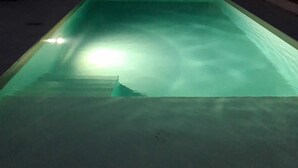 A rectangular swimming pool with a greenish hue, surrounded by a fence and a few chairs. - Maison à Louer Août 2024, Quartier Calme, Idéal Pour les Familles (Briatexte)