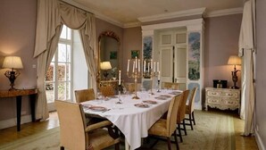 Un comedor formal con una larga mesa dispuesta para una comida, rodeada de sillas.