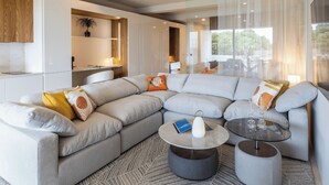 A modern living room with a grey sectional sofa, a round coffee table, and a glass-top side table. - Studio with direct access to the pool | Villa 5 (Pigeon-Pea Hill)