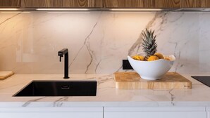 A modern kitchen with a wooden backsplash, a marble countertop, and a bowl of fruit. - Studio with direct access to the pool | Villa 5 (Pigeon-Pea Hill)