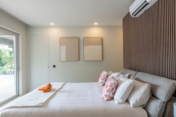 A modern bedroom with a large bed, a window with blinds, and two wall-mounted air conditioning units. - 2 rooms with private pool | Villa 1 (Pigeon-Pea Hill)