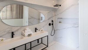 Un baño moderno con salpicadero de mármol, un espejo grande, tocador doble, cabezal de ducha de mano y estante empotrado.