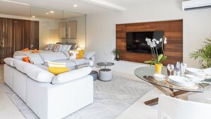 Ein modernes Wohnzimmer mit einer Couch, einem Couchtisch und einem Essbereich mit einem Glastisch und Stühlen.