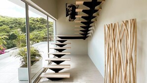 A modern interior with a staircase, a large window, and a view of greenery outside. - 2 rooms ocean view and jacuzzi | Villa 8 (Pigeon-Pea Hill)