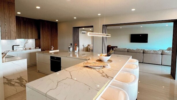 A modern kitchen with a marble island, bar stools, and a dining area with a sofa. - 2 rooms ocean view and jacuzzi | Villa 8 (Pigeon-Pea Hill)