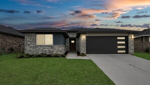 A modern two-story house with a brick facade, a garage, and a well-maintained lawn. - Rammies Exquisite 4BR in Katy (katy)