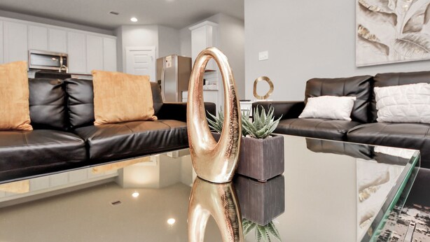 A modern living room with two black leather sofas, a glass coffee table, and decorative items. - Rammies Exquisite 4BR in Katy (katy)