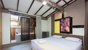 Un dormitorio moderno con una cama grande, un vidrio corredero que da a un baño y una pared de acento de mármol.