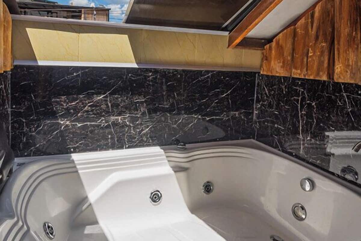 Een moderne badkamer met een ruime badkuip, marmeren wanden en een houten plafond.