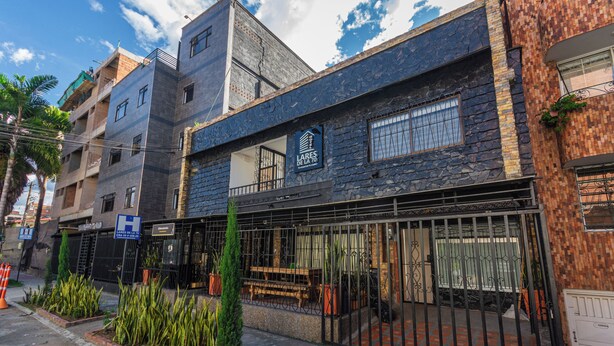 Un edificio de varios pisos con fachada de piedra, entrada protegida por una reja y un letrero que indica un centro médico.