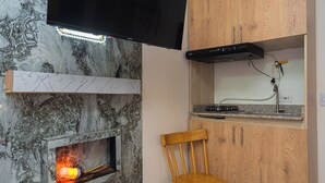 Cocina compacta con televisor integrado, un mueble de madera, un pequeño rincón de descanso y una chimenea.