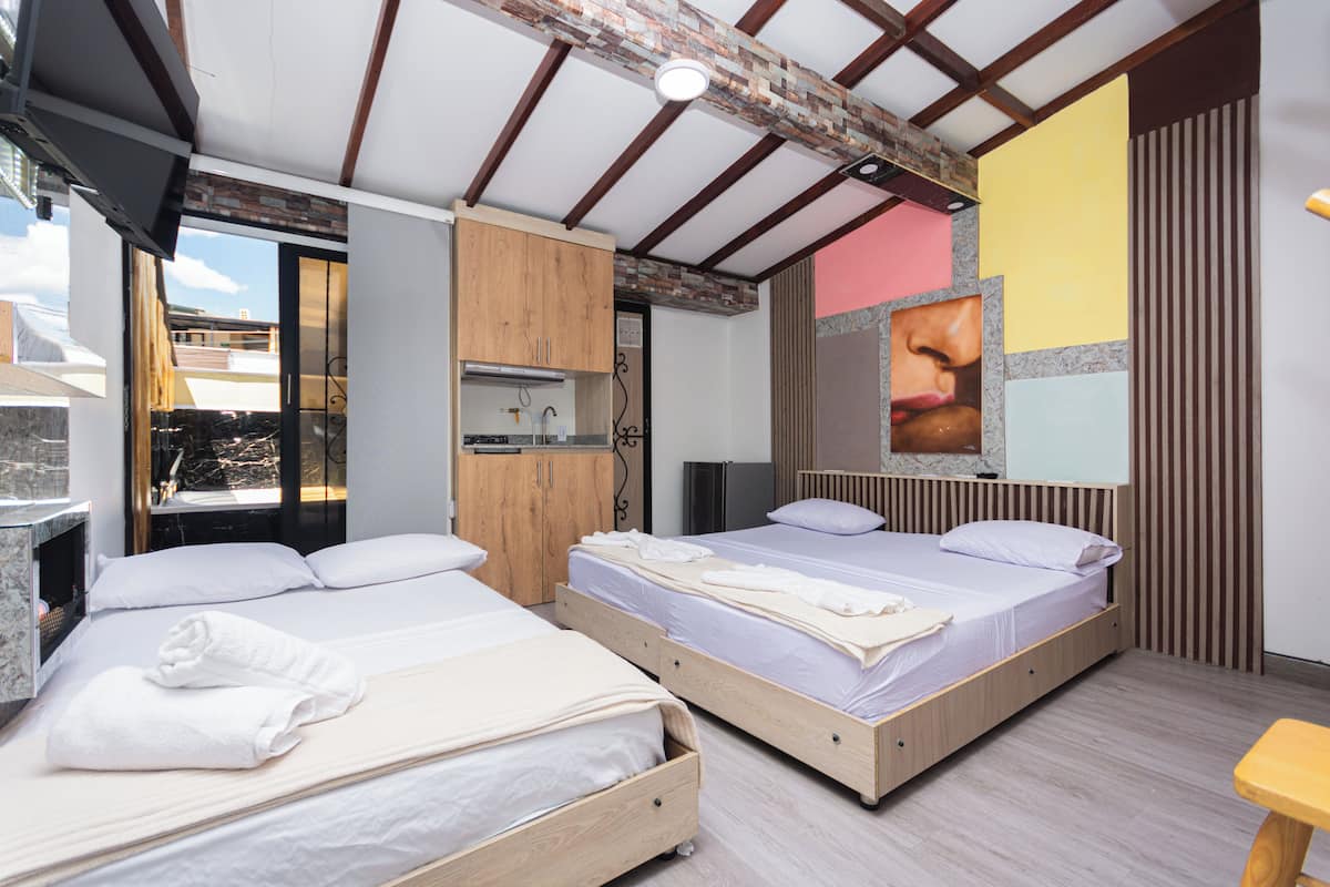 Een moderne hotelkamer met twee houten bedden, een badkamer met een marmeren wastafel en een groot raam met uitzicht op de stad.