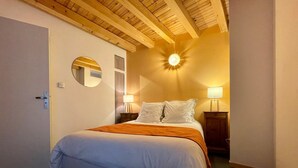 A bedroom with a bed, two bedside tables with lamps, a mirror, and a ceiling light fixture.