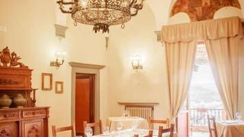 A dining area with a chandelier, wooden chairs, and tables set for dining.