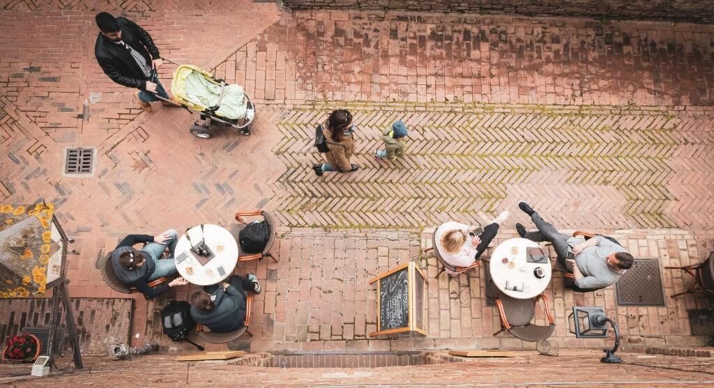 An overhead view of a courtyard with brick flooring, outdoor seating areas, and a small stage.