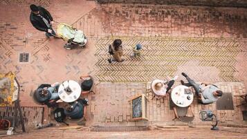 An overhead view of a courtyard with brick flooring, outdoor seating areas, and a small stage.