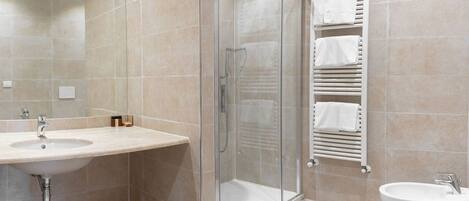 A modern bathroom with a glass-enclosed shower, a sink, and a toilet.