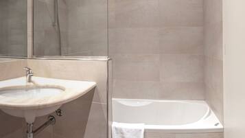 Ein Badezimmer mit Waschbecken, Spiegel, Dusche und Badewanne.