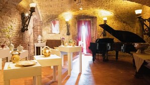 A rustic room with exposed brick walls, a piano, and a dining table set with white tableware.