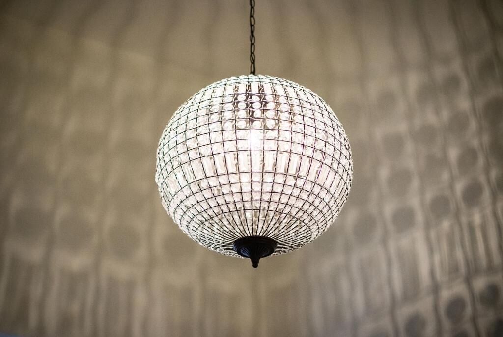 Una lámpara esférica con diseño de cuadrícula, suspendida de una cadena.