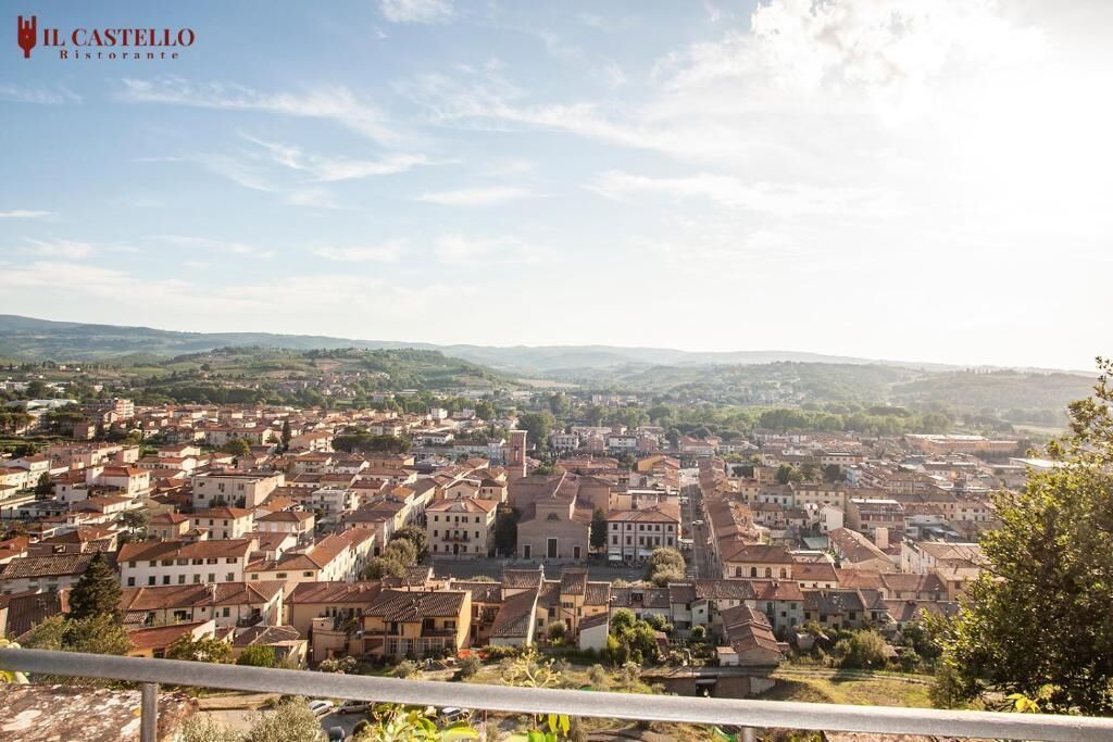 Vista panorámica de un pueblo con una mezcla de edificios históricos y modernos, cielo despejado y un paisaje montañoso distante.