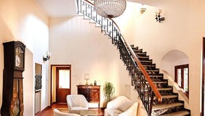 A staircase with a wooden handrail and black balusters, leading to an upper floor.