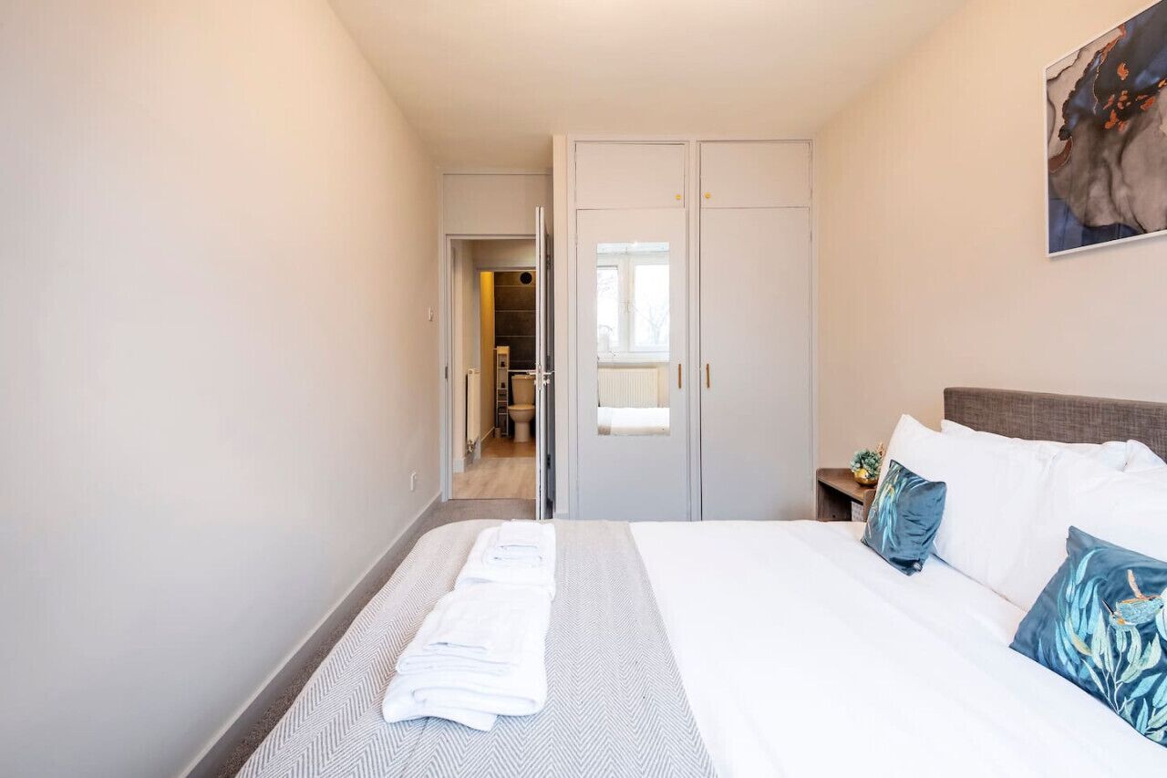 A hotel room with a bed, a nightstand, a wardrobe, and a bathroom visible through an open door.