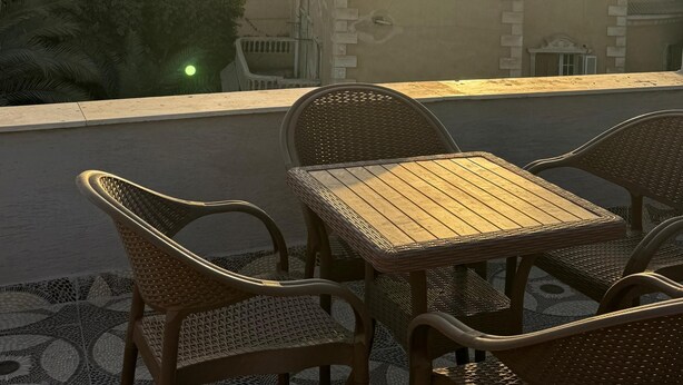 A terrace with wicker furniture and a view of the pyramids at sunset. - Exotic Pyramids hotel  (Giza)