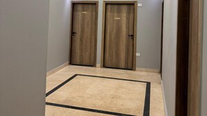 A hallway with two wooden doors, a tiled floor, and recessed lighting on the ceiling. - Exotic Pyramids hotel  (Giza)