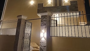 A multi-story building with a modern design, featuring balconies, a gated entrance, and multiple light fixtures. - Exotic Pyramids hotel  (Giza)