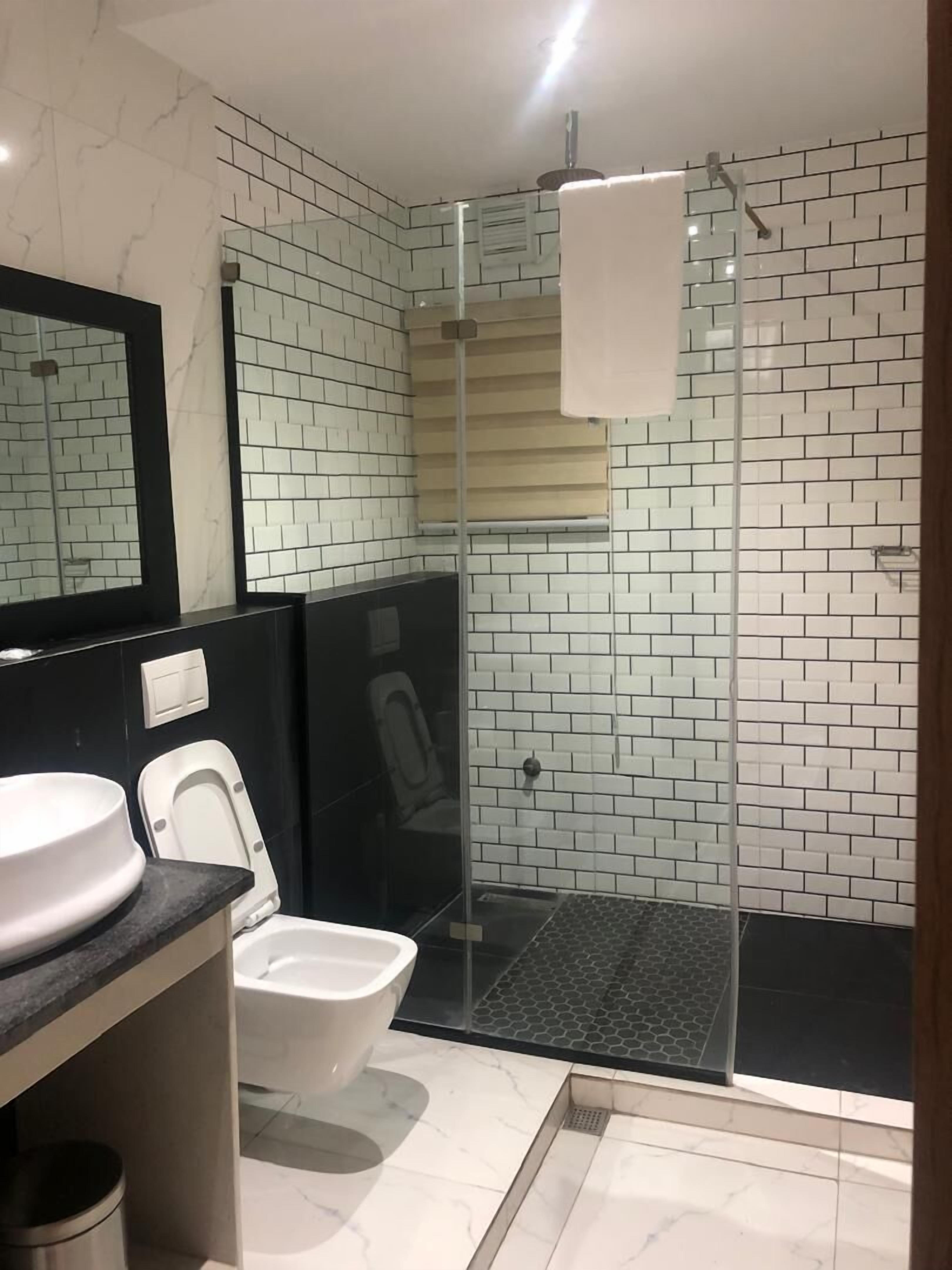 Une salle de bain avec une douche à parois de verre, des toilettes blanches et un lavabo avec un miroir.